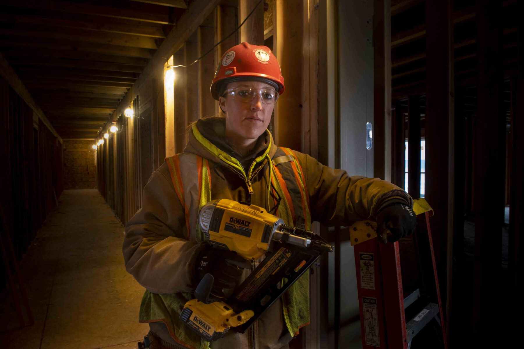 Female sprinkler fitter during construction holding DeWalt drill