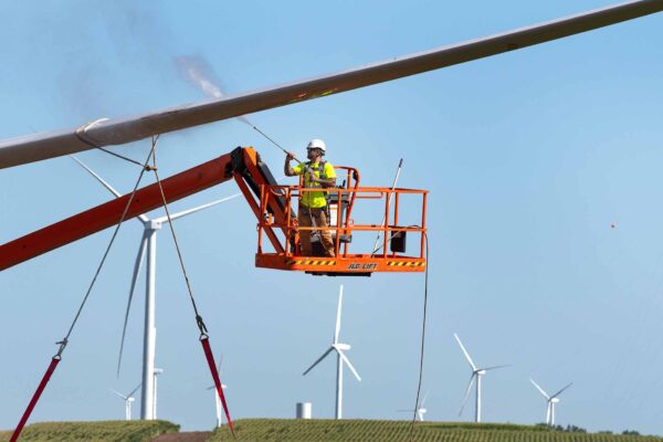 Laborer spraying water on wind turbine blade
