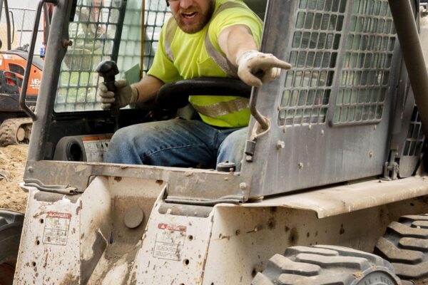 Operating Engineer driving a skid loader on construction site