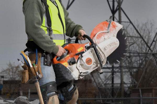 Woman cement mason holding giant Stihl saw